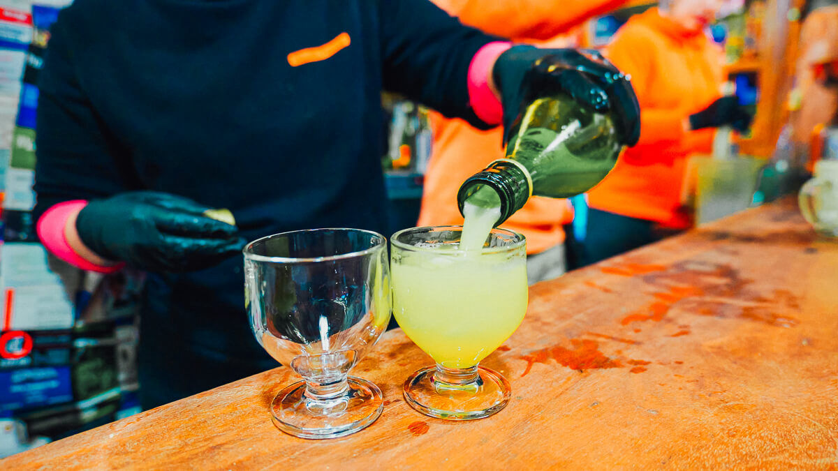 A person is filling up a glas of local poncha in a glas on the counter